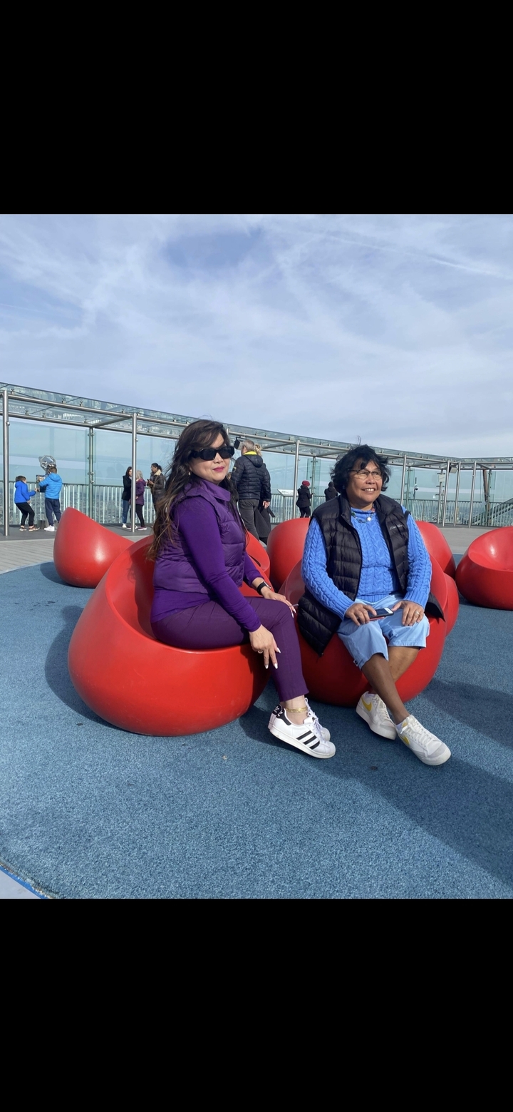 Deux femmes assises sur des sièges colorés dans un espace sur le toit.