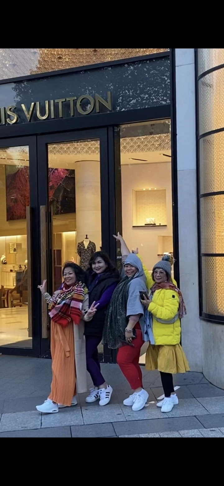 Groupe de femmes posant devant un magasin.