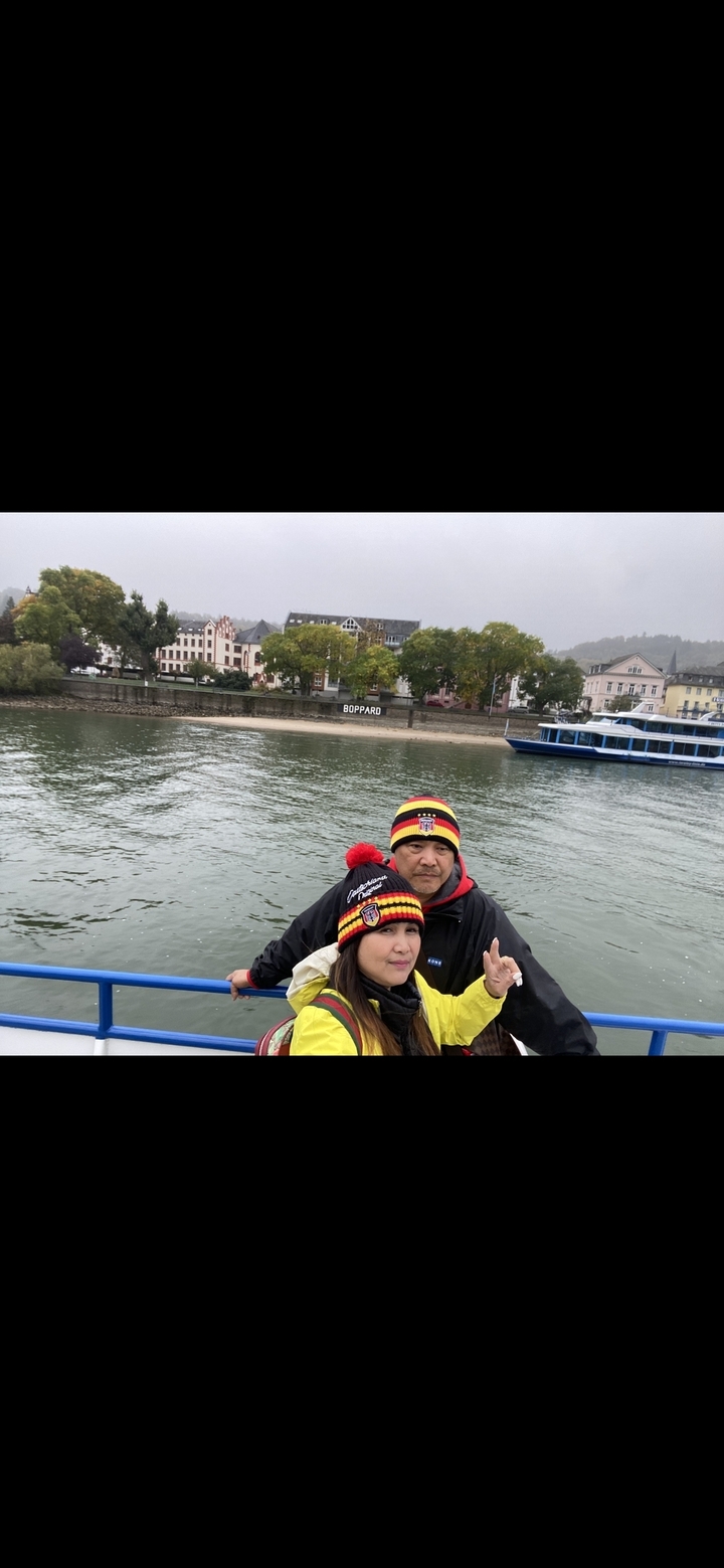 Couple posant au bord d'une rivière avec des bâtiments en arrière-plan.