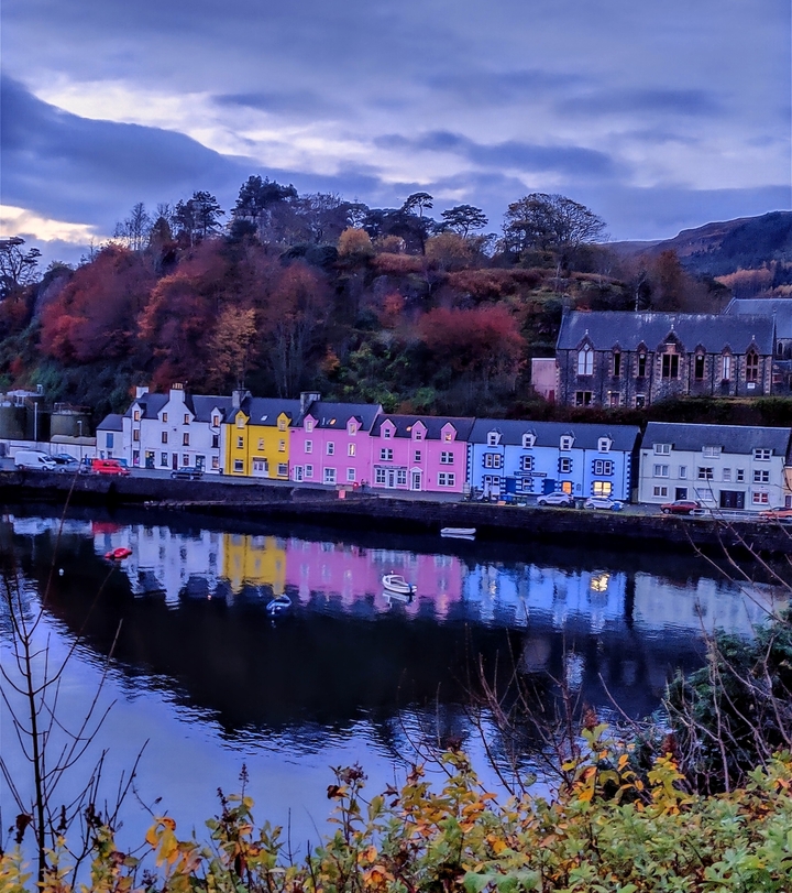 Colorful houses reflecting on a calm water surface.