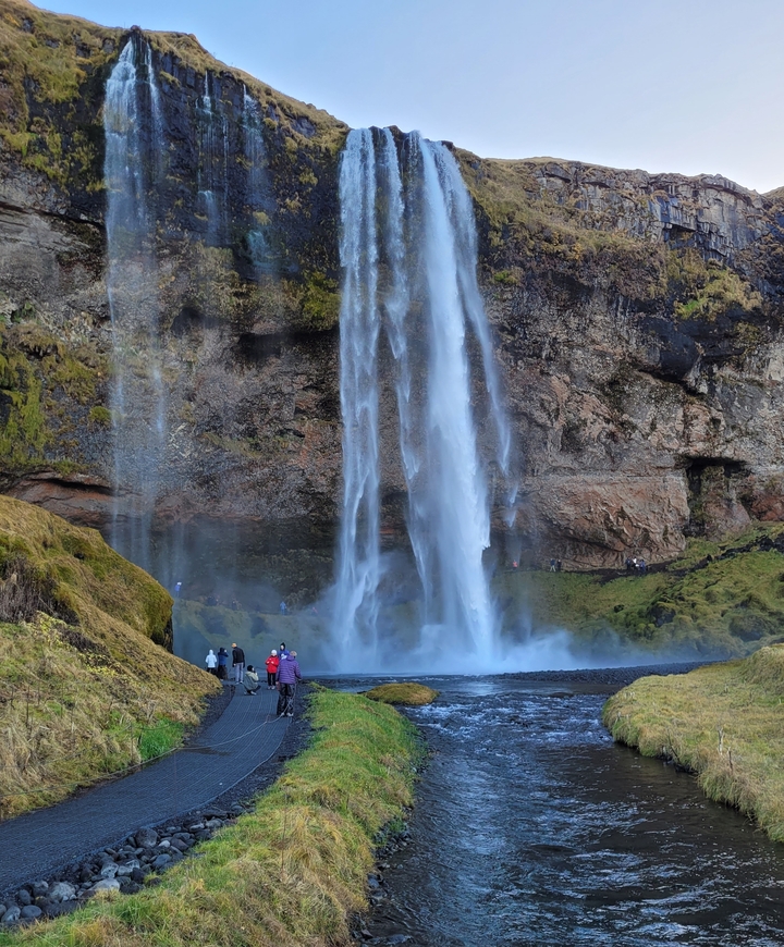 Gran cascada cayendo sobre las rocas, con personas cerca para dar escala.