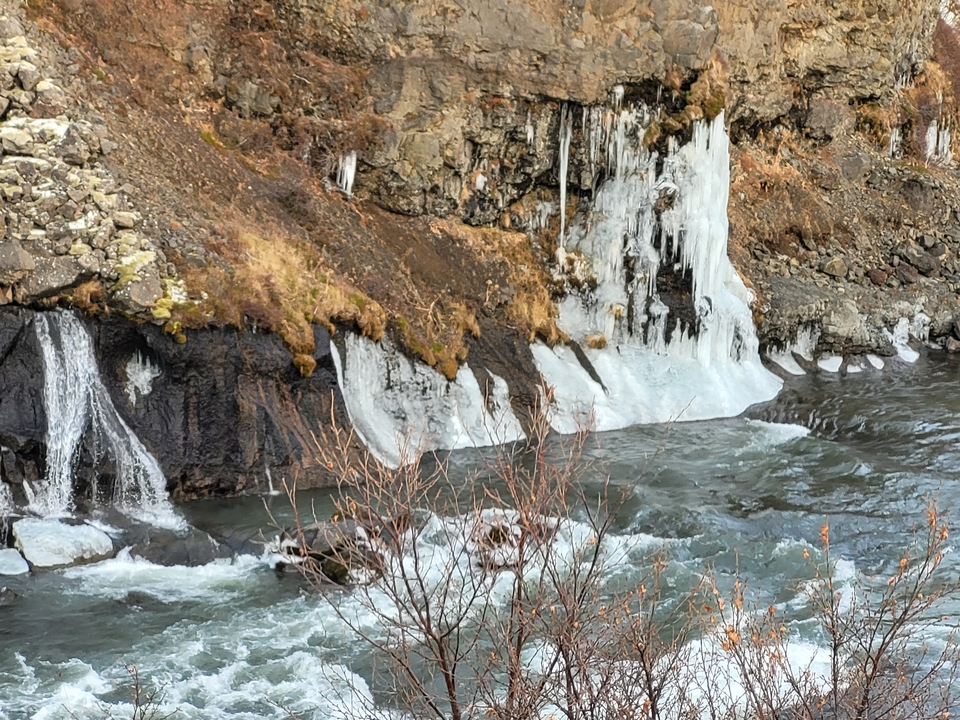 Cascada helada con agua corriendo y paisaje invernal.