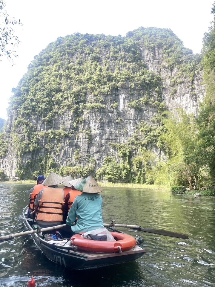 Des gens en tenue traditionnelle ramant dans une barque sur une rivière.