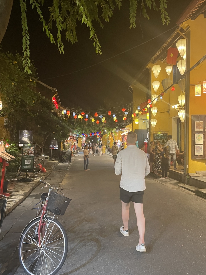 Une rue éclairée par des lanternes grouillant de monde pendant la soirée.