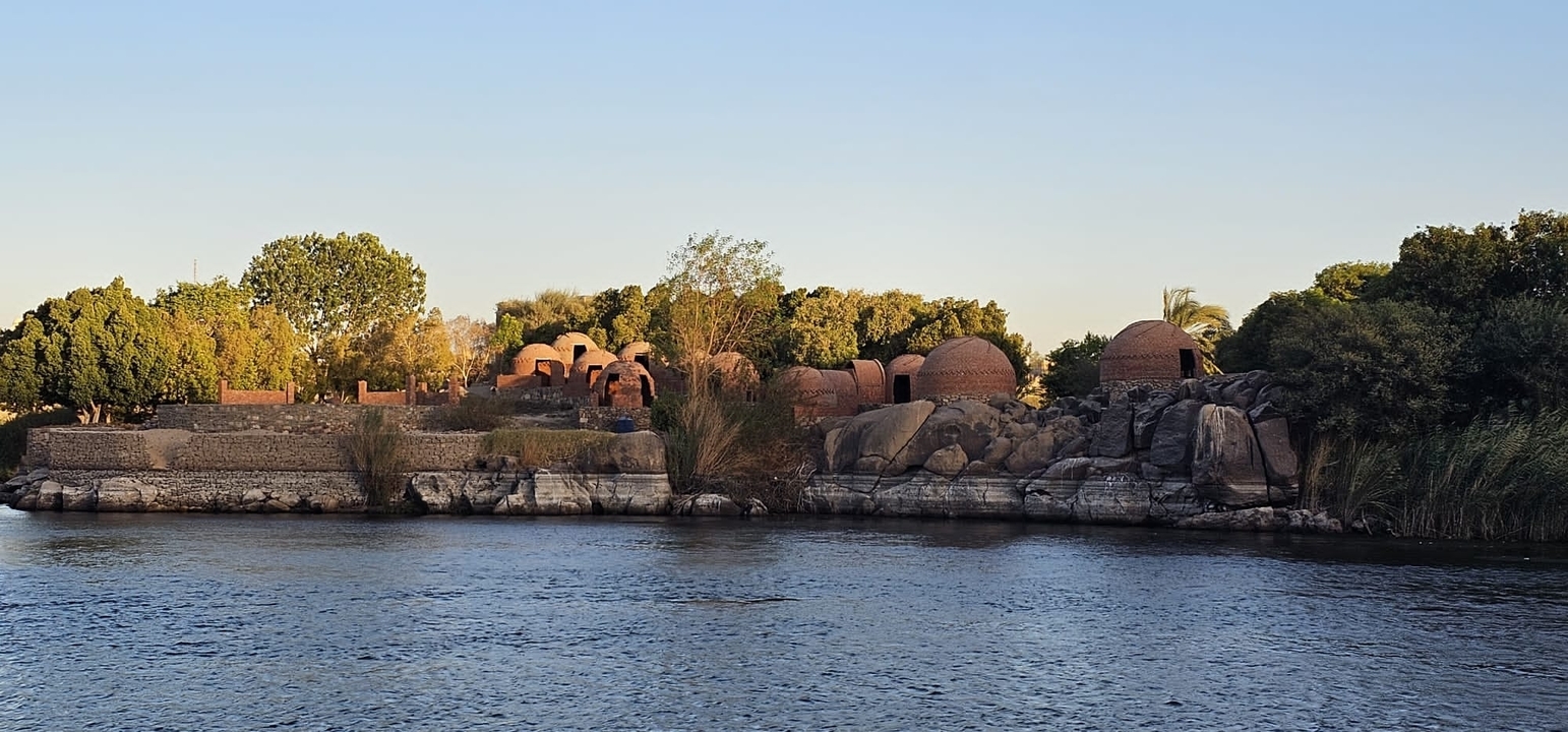 Riverbank with ancient structures and lush greenery.