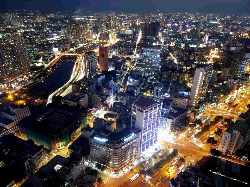 Vue aérienne nocturne d'une ville avec des rues et des bâtiments illuminés.