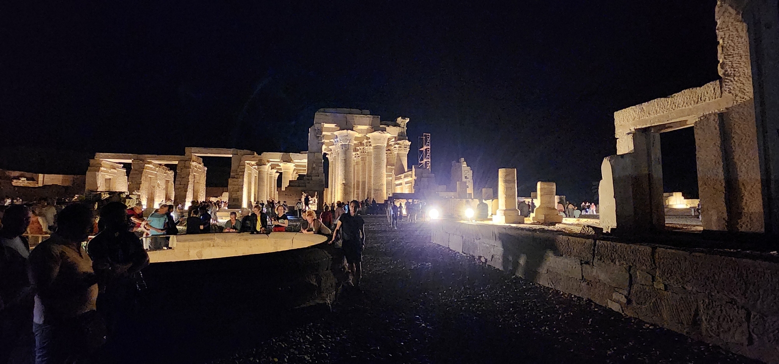 Ancient ruins lit at night with a group of tourists.