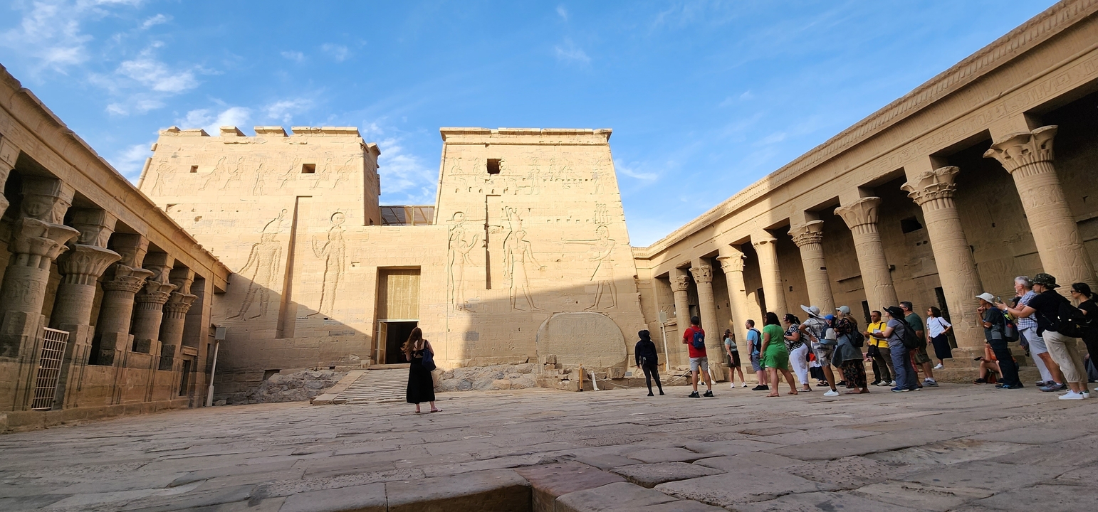 Tourists exploring ancient Egyptian temples with hieroglyphs.