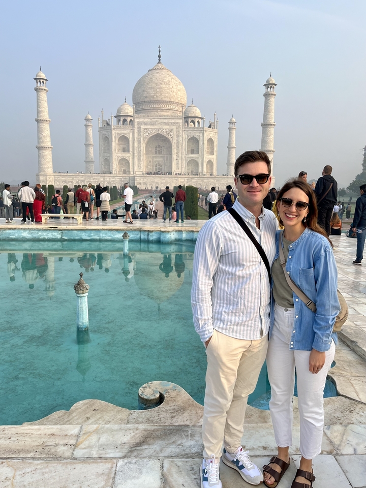 Des gens debout devant le Taj Mahal avec reflet dans l'eau.