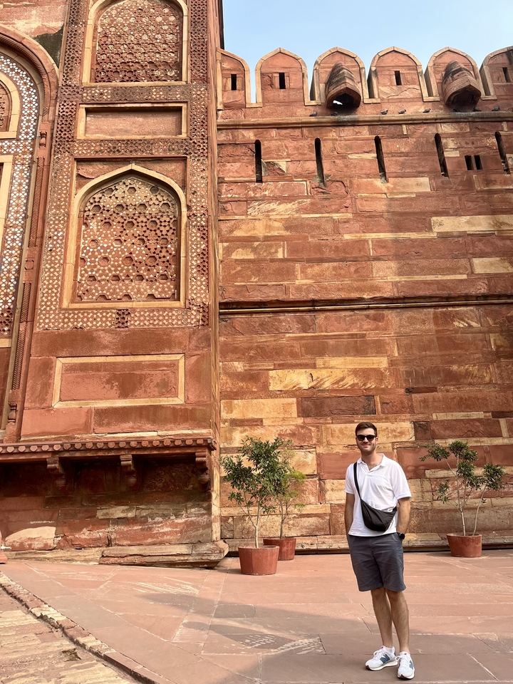 Personne debout devant une architecture en grès rouge.