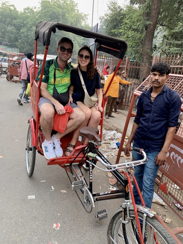 Un couple assis dans un pousse-pousse avec un conducteur prêt à les emmener.