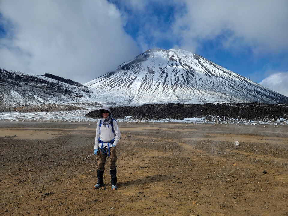 Randonneu se tenant debout devant un sommet de montagne enneigé.