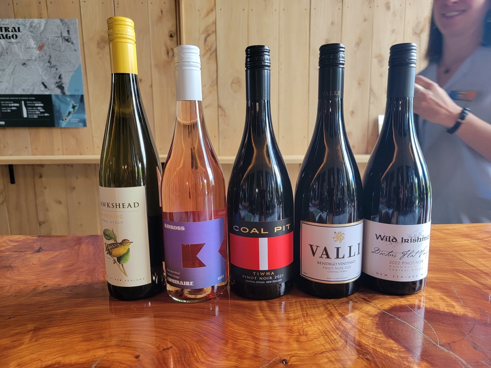 Cinq bouteilles de vin exposées sur un comptoir en bois.