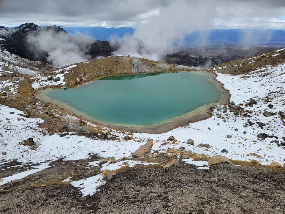 Lac émeraude entouré d'un terrain enneigé.