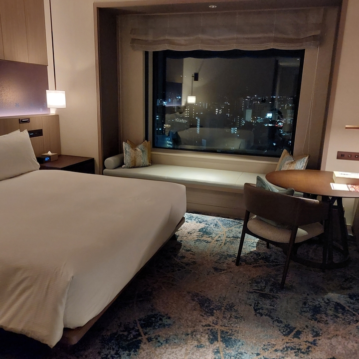 Well-furnished hotel room at night with a city view.