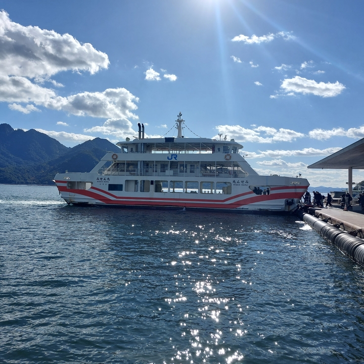 Passenger ferry docked at a pier with mountains in the background.