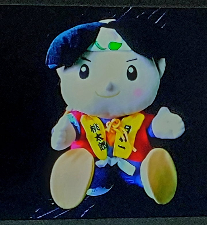 Stuffed toy with vibrant colors against dark background.