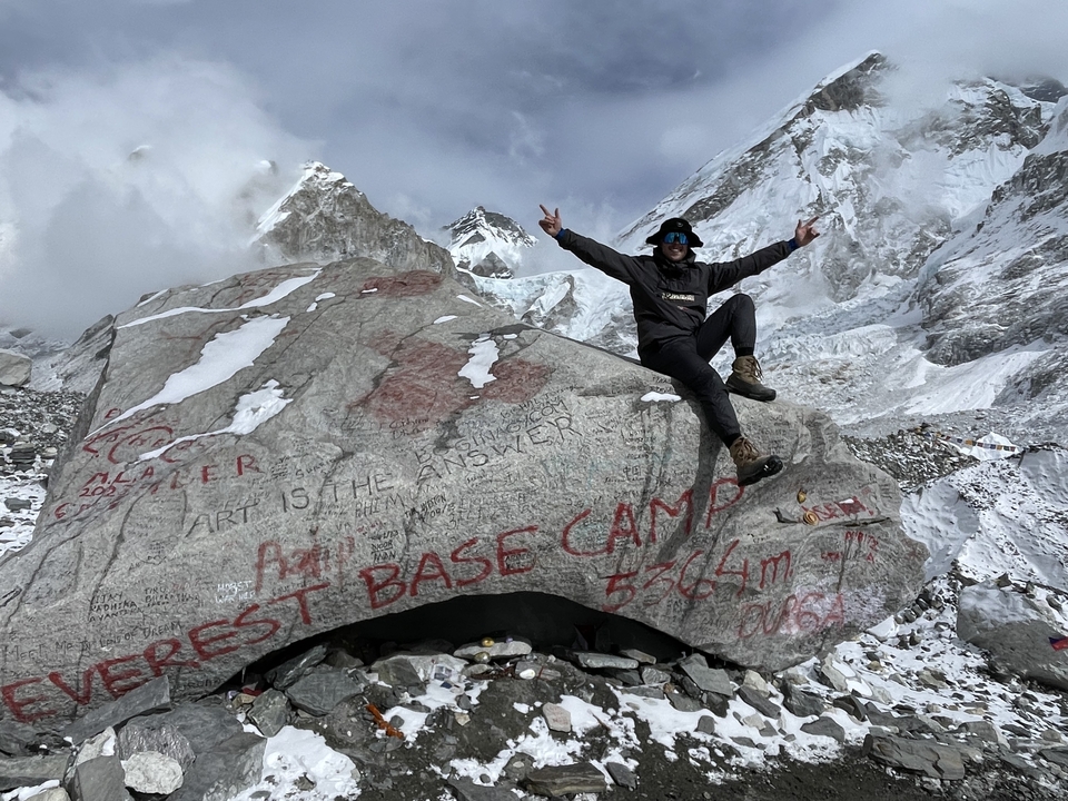 Person sitting on a boulder with Everest Base Camp in the background.