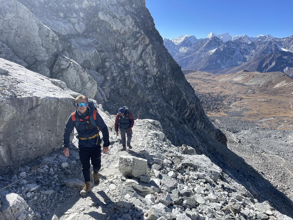 Hikers traversing a rocky mountain trail with a panoramic view of the landscape.