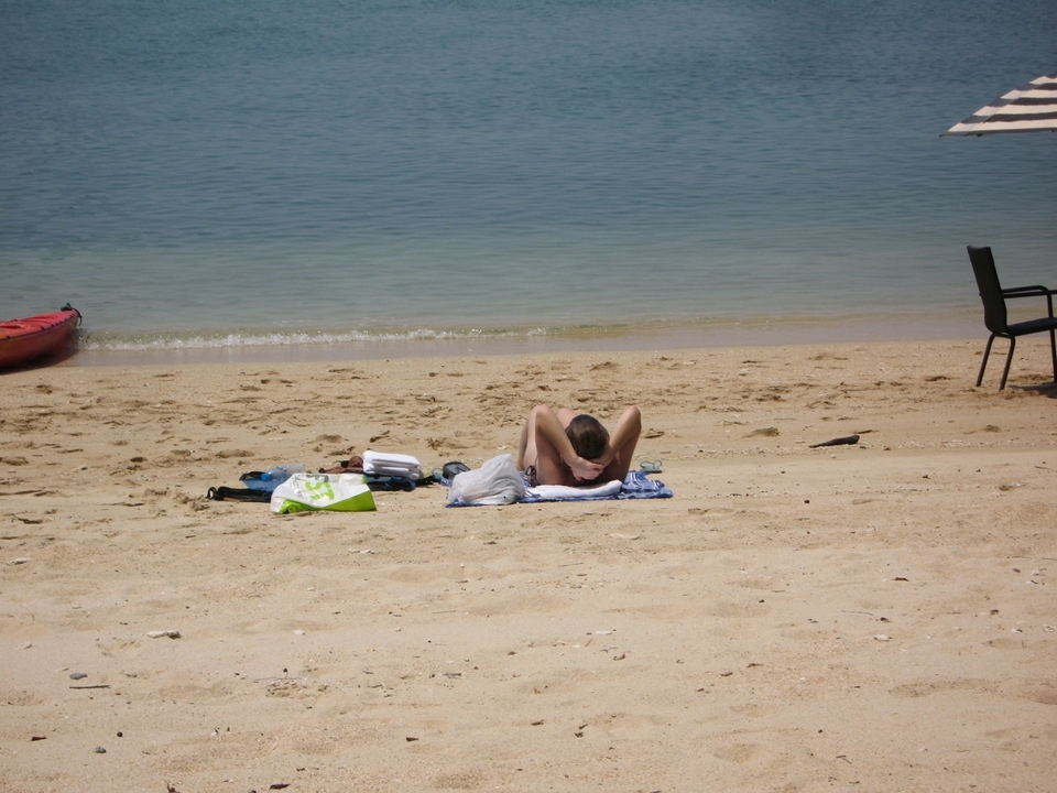 Personne se prélassant sur une plage avec un kayak à proximité.