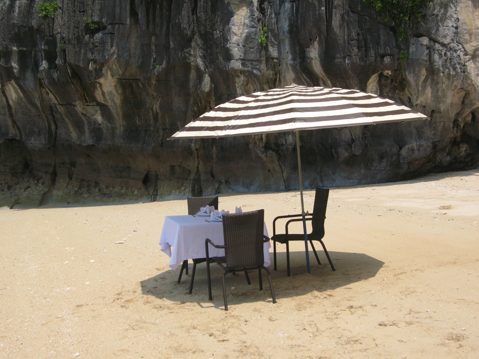 Table et chaises avec parasol sur une plage au bord de falaises.