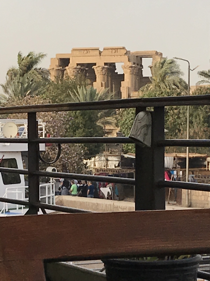 Des personnes visibles à travers une rambarde avec un bateau en arrière-plan.