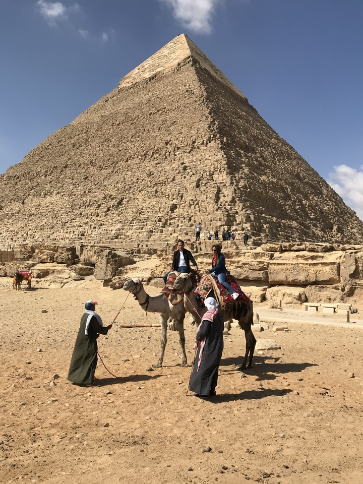 Deux personnes montant des chameaux près de la Grande Pyramide de Gizeh.