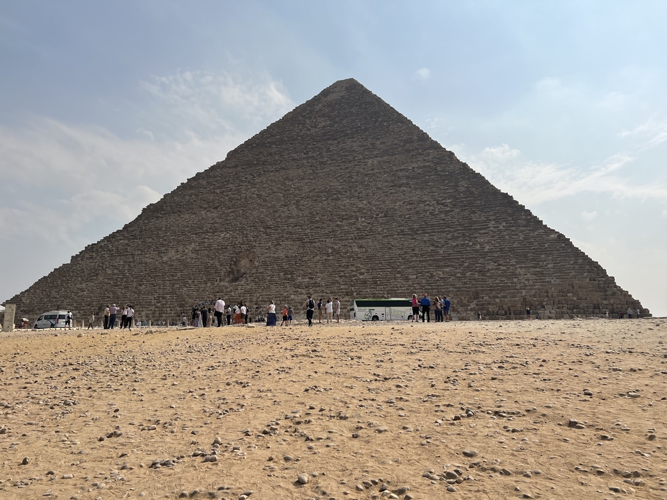Grande pyramide avec des touristes rassemblés à la base.