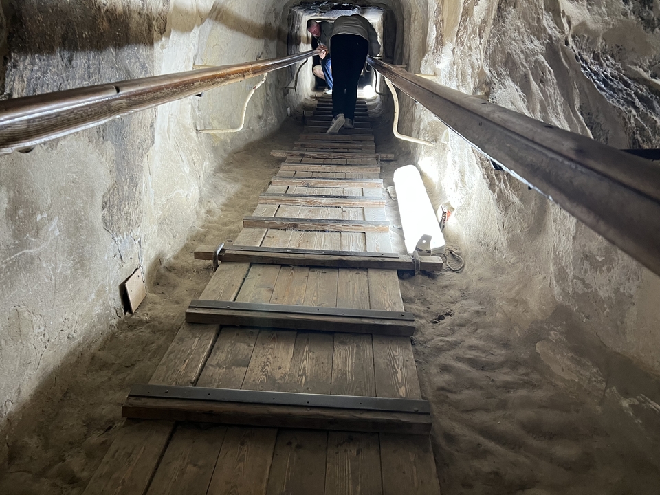Passage étroit à l'intérieur d'une structure en pierre avec une personne qui traverse.