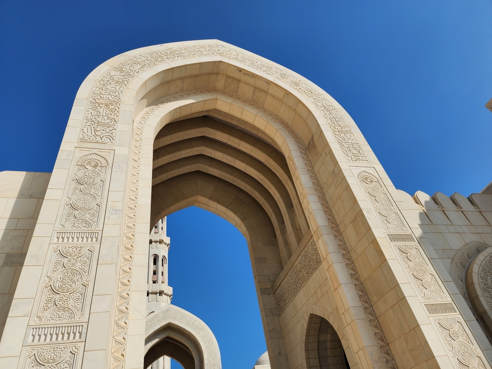 Architectural arch with intricate designs against a clear blue sky.