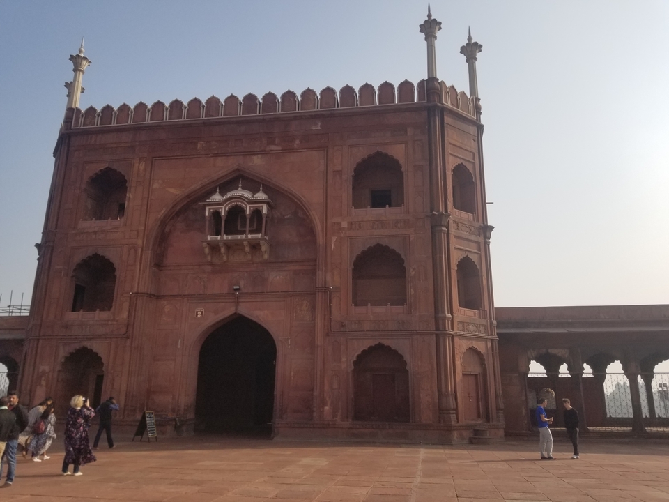 Rood fortachtig gebouw met een paar mensen eromheen.