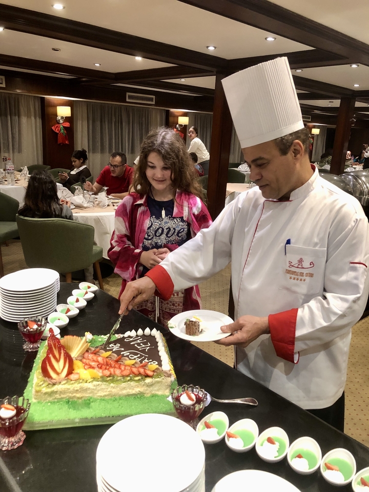 Un chef préparant un plat avec une jeune fille qui observe.
