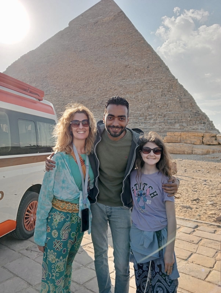 Un groupe de personnes devant une structure pyramidale avec un van.