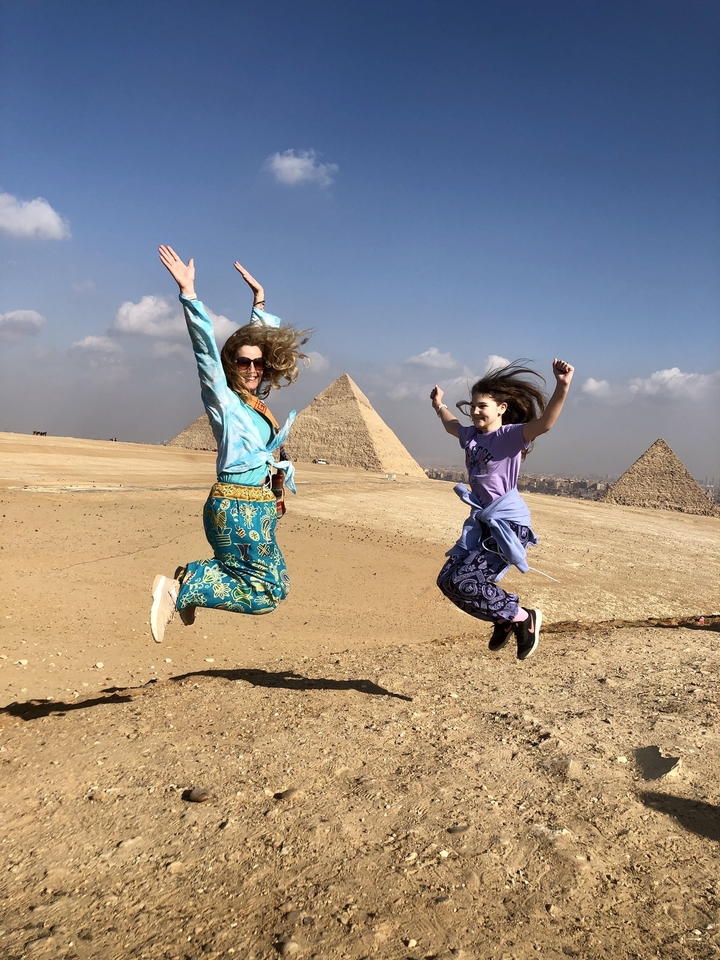 Des gens qui sautent avec des pyramides en arrière-plan.