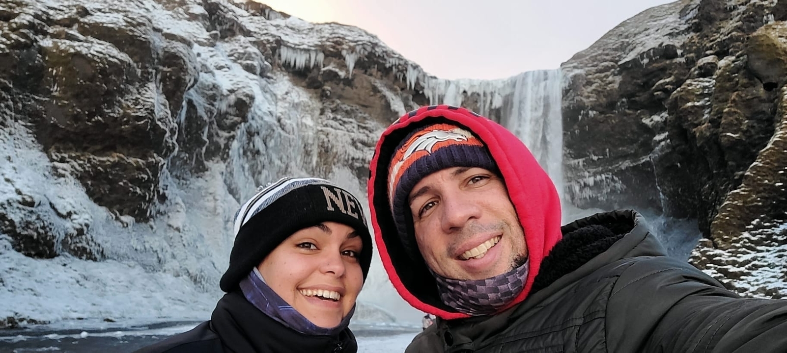 Couple taking a selfie in front of a frozen waterfall.