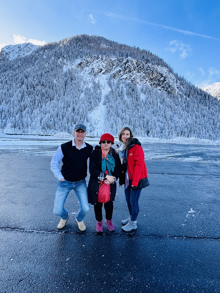 Three people posing in a snowy landscape with pine trees.
