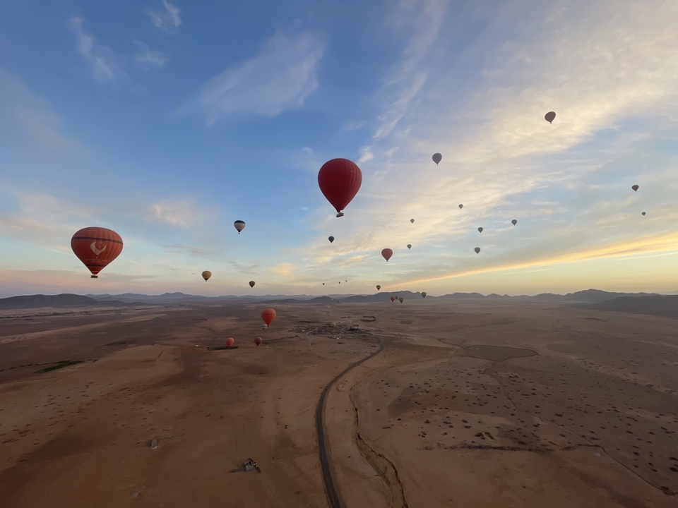 Hot air balloons flying over an expansive desert landscape.