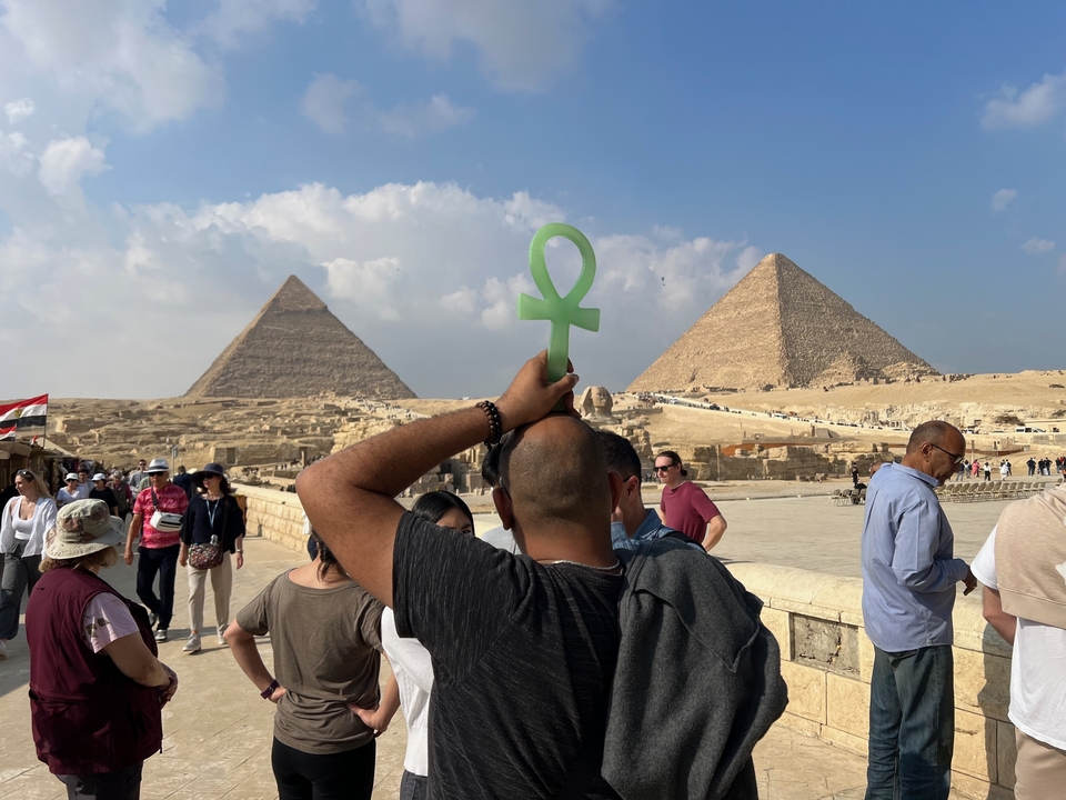 Touristes aux Pyramides de Gizeh tenant une croix ansée.