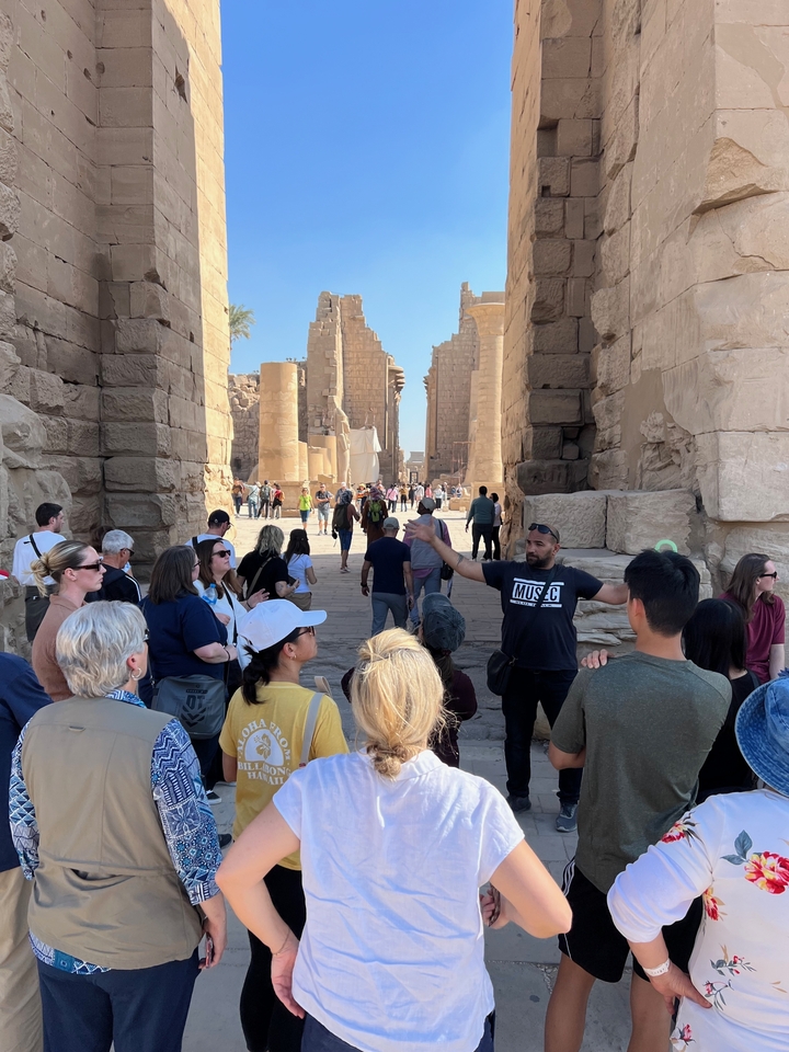 Visite de groupe animée à l'intérieur d'un temple égyptien antique avec un guide.