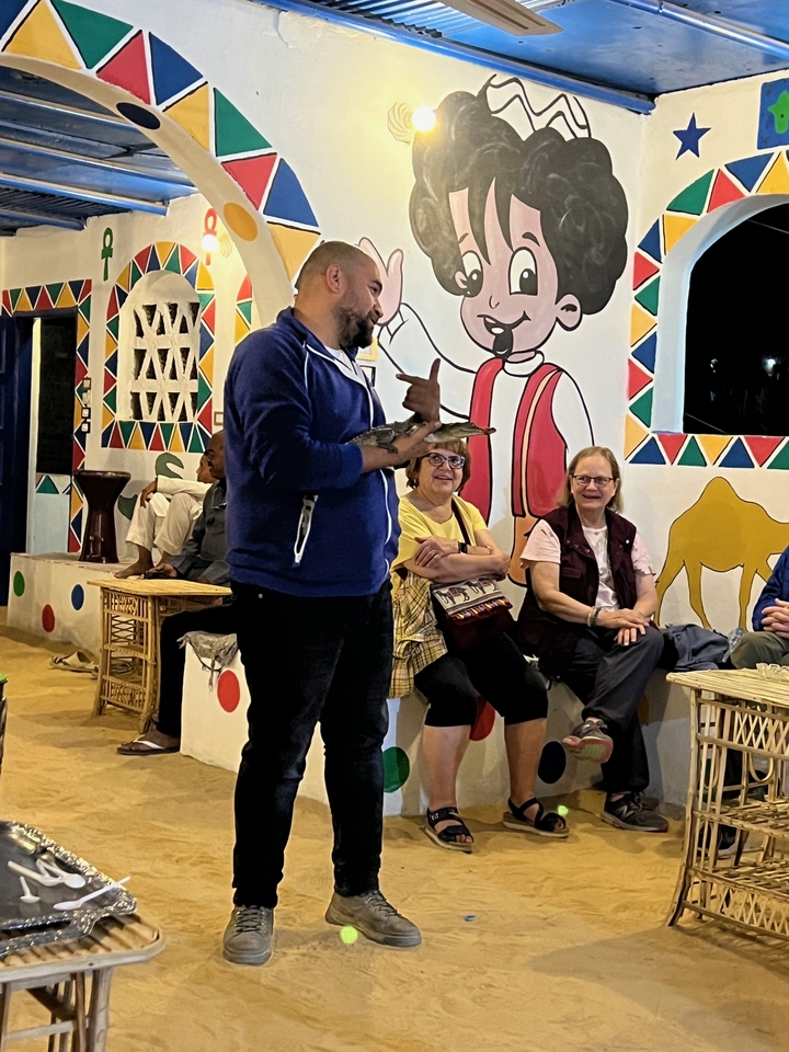 Un groupe de personnes assises qui profitent d'un spectacle culturel avec des peintures au mur.