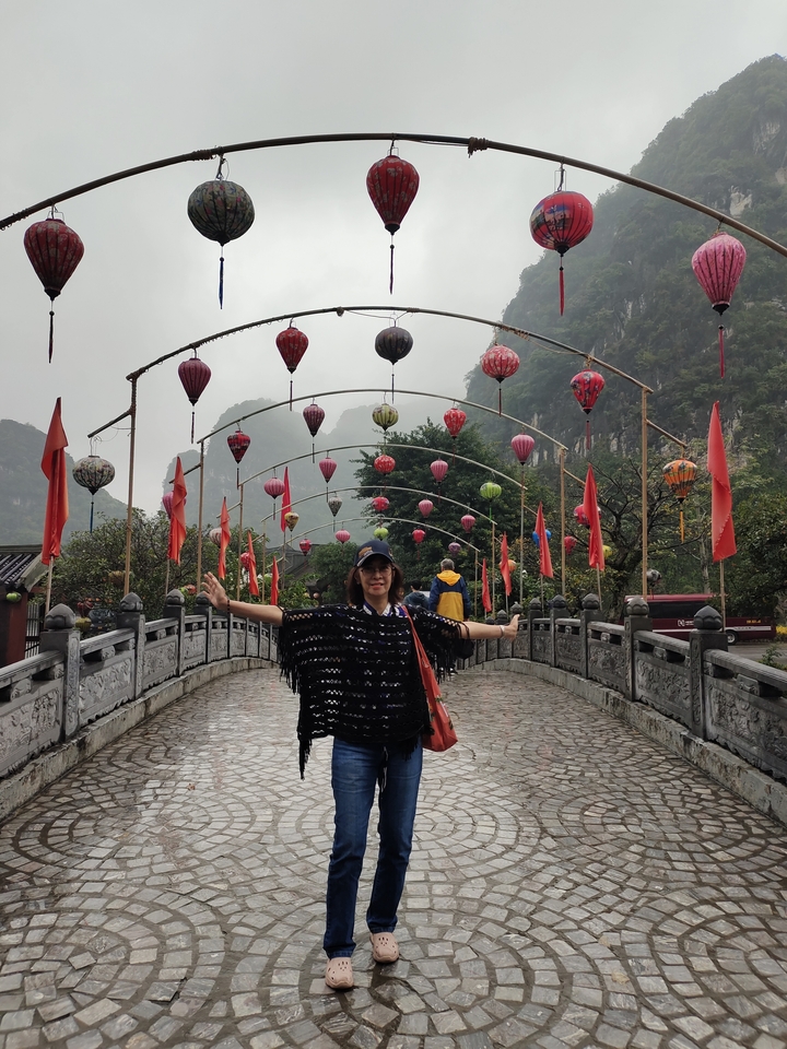 Pont décoré de lanternes, avec des personnes qui le traversent à pied.