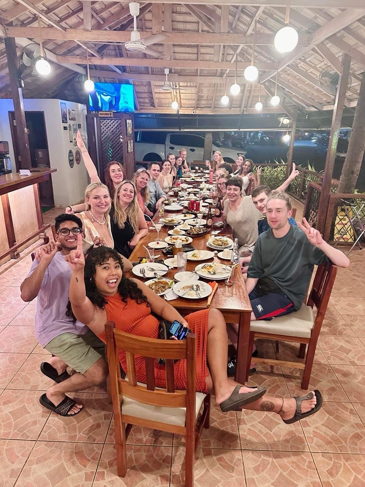 Groupe de personnes dînant à une longue table, posant pour une photo.