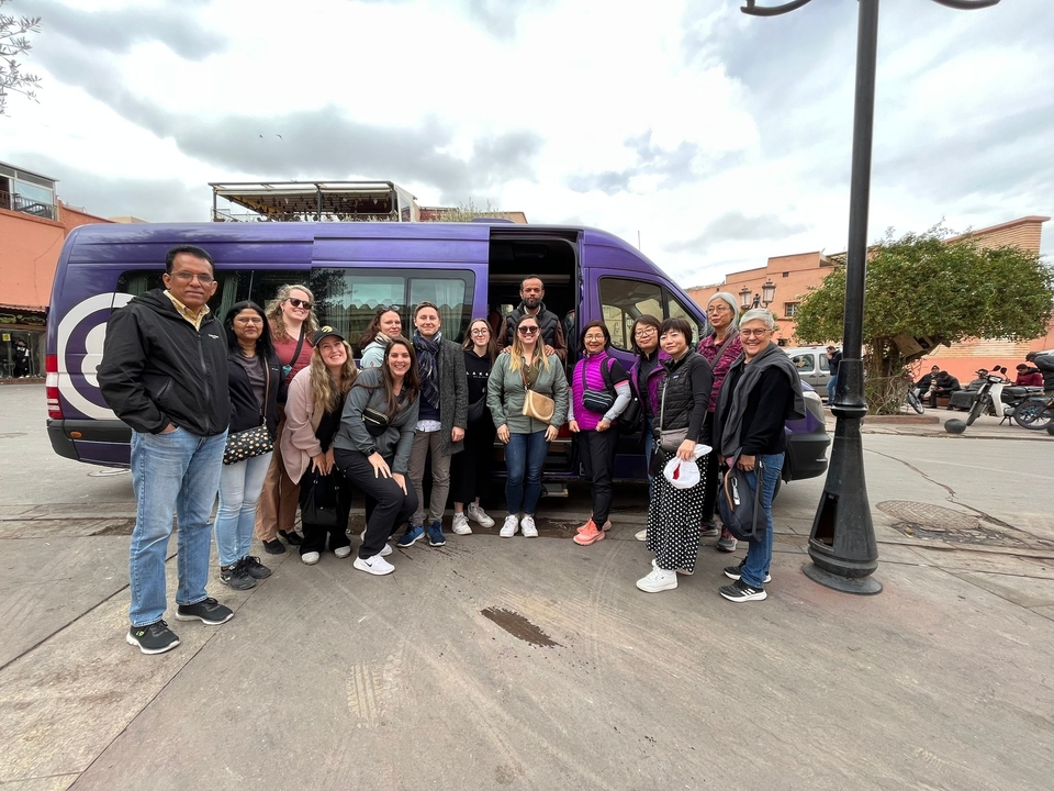 Group photo in front of a van with a diverse group of people.