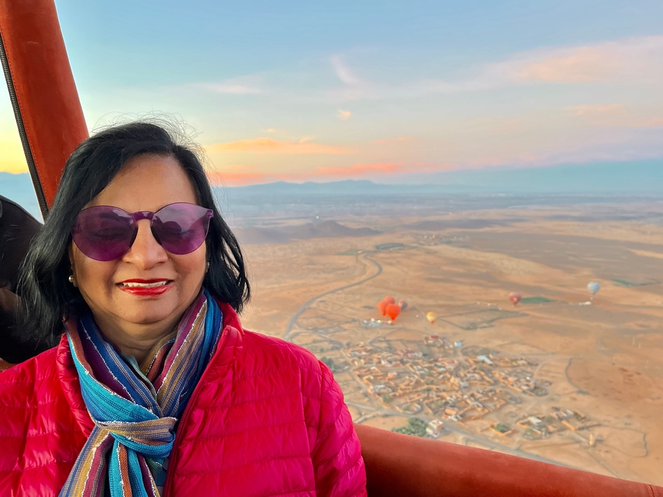 Woman in a hot air balloon basket with landscape view