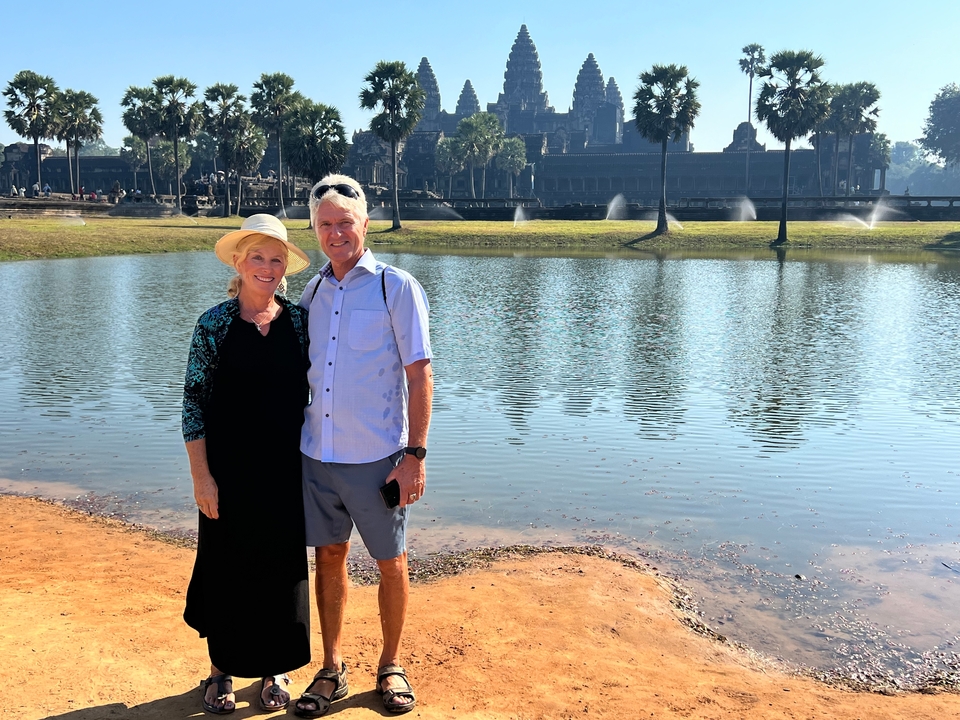 Couple debout près d'un lac avec Angkor Vat en arrière-plan.