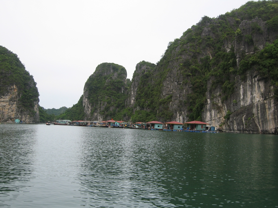 Waterfront view with floating homes and towering karst formations.