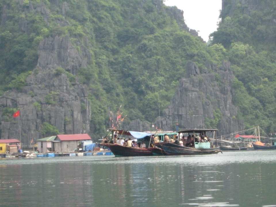 Image floue de bateaux sur un lac calme avec des falaises rocheuses.