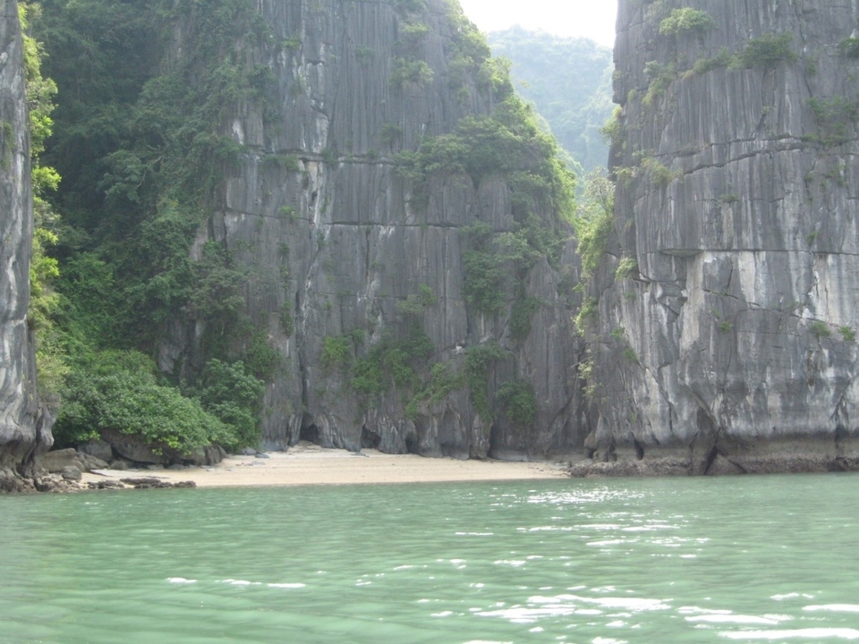 Plage entourée de hautes formations rocheuses.
