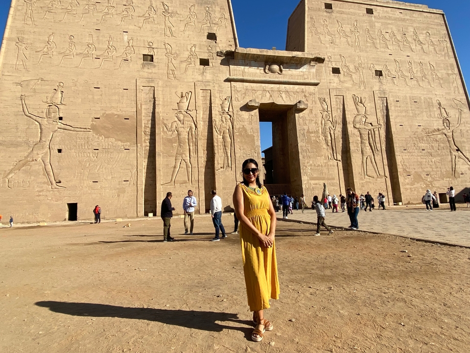 Personne portant une robe jaune devant le temple d'Edfou.
