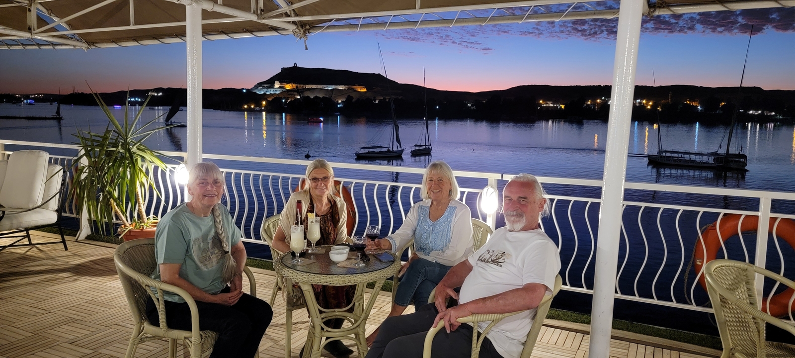 Group of people sitting on a boat deck at sunset.
